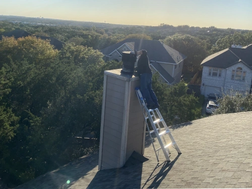 technician cleaning chimney on the roof